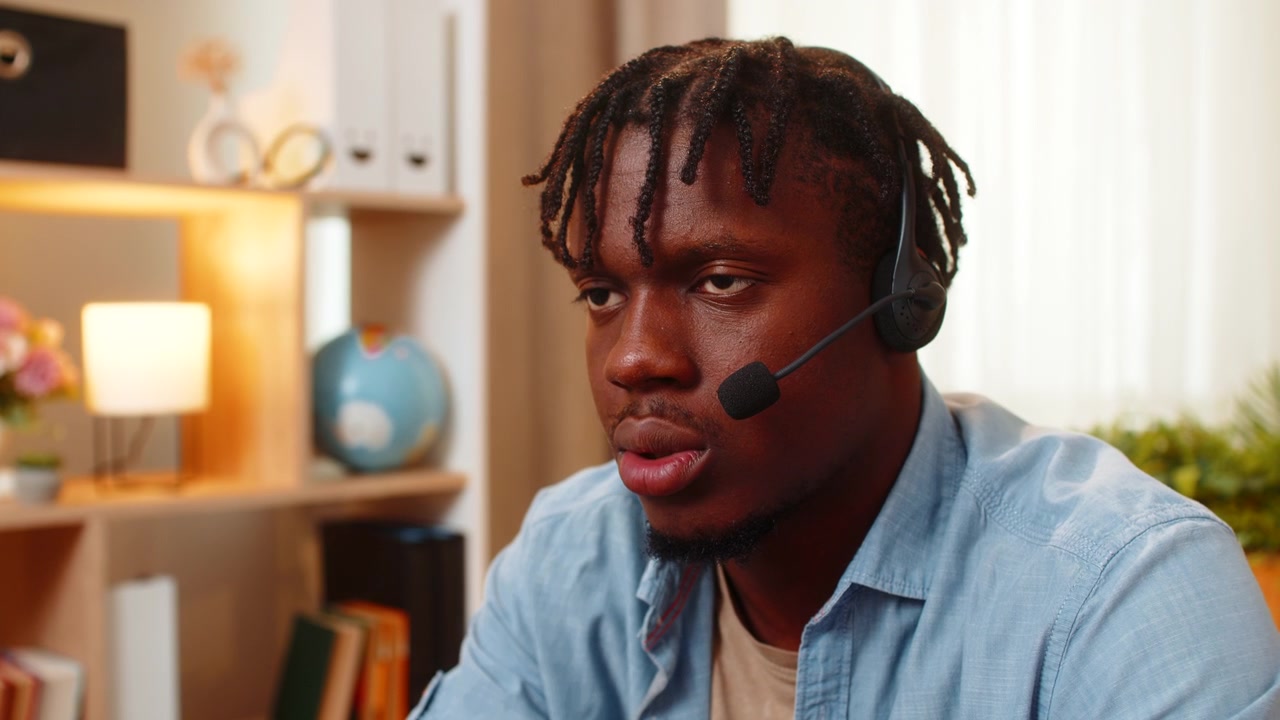 African american young man on home table talking with client as call center operator wearing headset