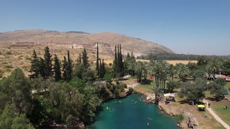 aerial view away from a emerald lagoon, in gan hashlosha, israel - reverse, drone shot