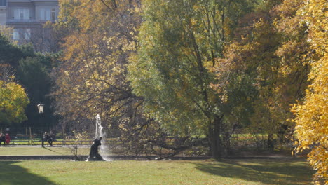 beautiful sunny afternoon in the burggarten park in vienna with people sitting in front of a fountain and enjoying the sun