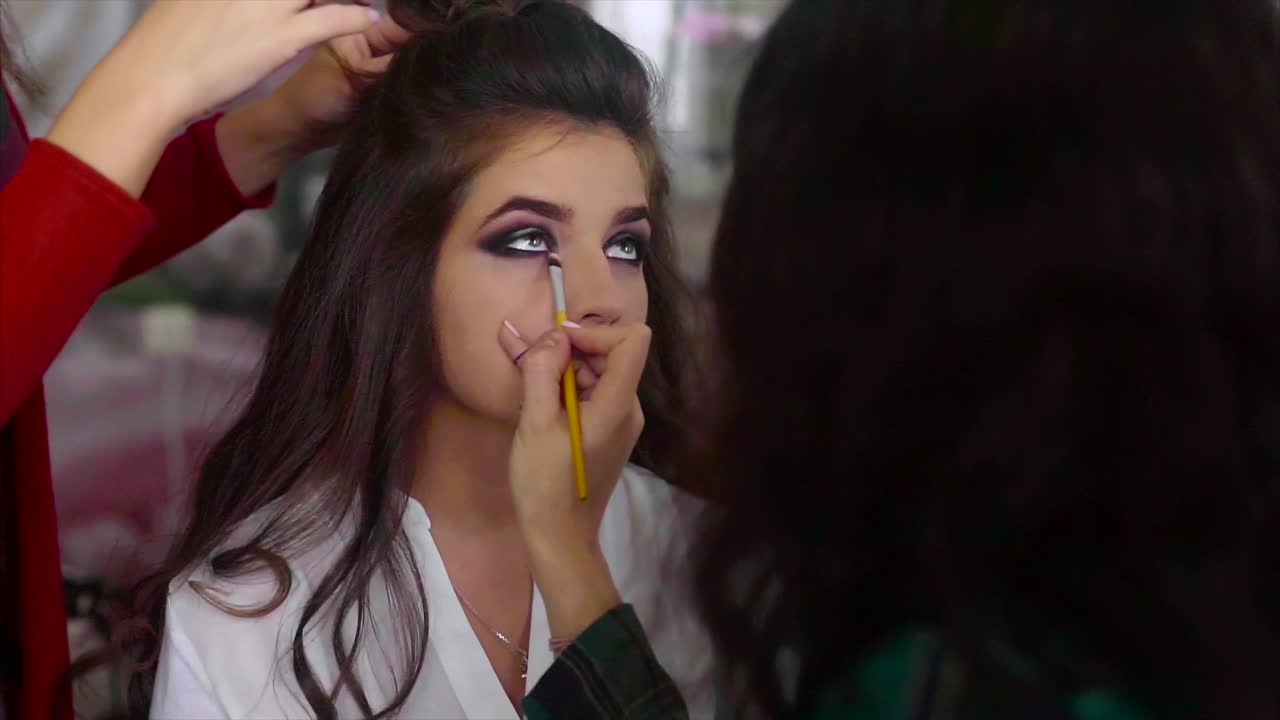 artista de maquillaje aplicando maquillaje a una mujer