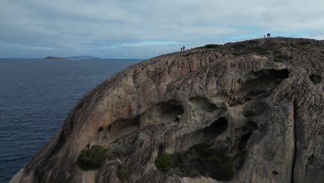 Drohne-Fliegt-In-Richtung-Frenchman-Peak,-Australien,-Mit-Wanderern-Und-Dem-Pazifischen-Ozean-Im-Hintergrund