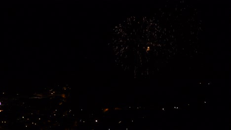 celebración con coloridos y brillantes fuegos artificiales, sobre un pueblo de montaña, por la noche