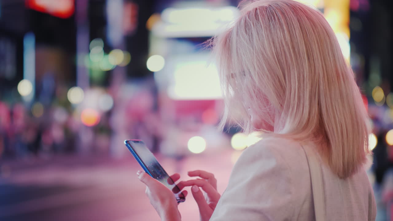 una mujer usa un teléfono inteligente en una calle concurrida de manhattan las gotas de lluvia caen en la pantalla