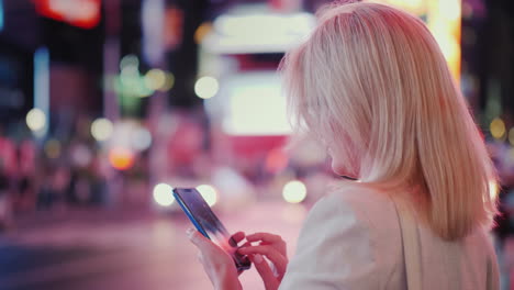 una mujer usa un teléfono inteligente en una calle concurrida de manhattan las gotas de lluvia caen en la pantalla