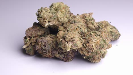 cannabis buds or nugs in a white background. the surface moves around and stoped with the marijuana in frame.