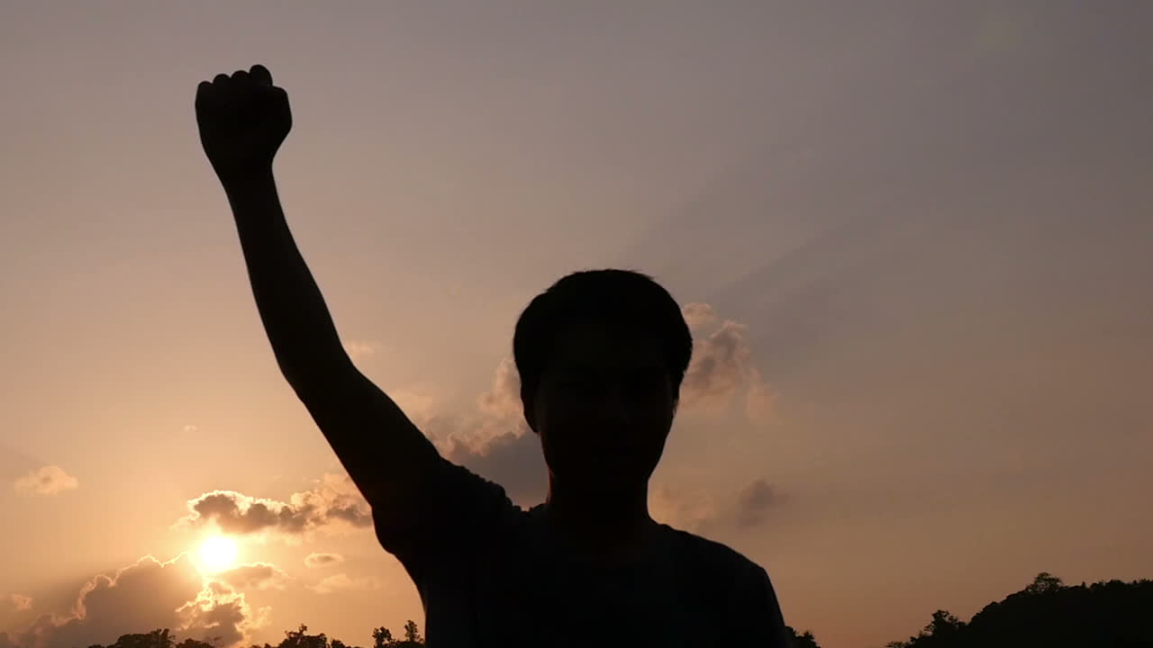 Silhouette of a person raising a fist at sunset