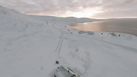 Dolly-Vorwärts-In-Richtung-Farm-Mit-Schnee-Bedeckt-Am-Meeresufer,-Island