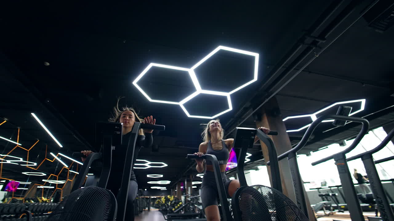 Two women working out on exercise bikes in a gym