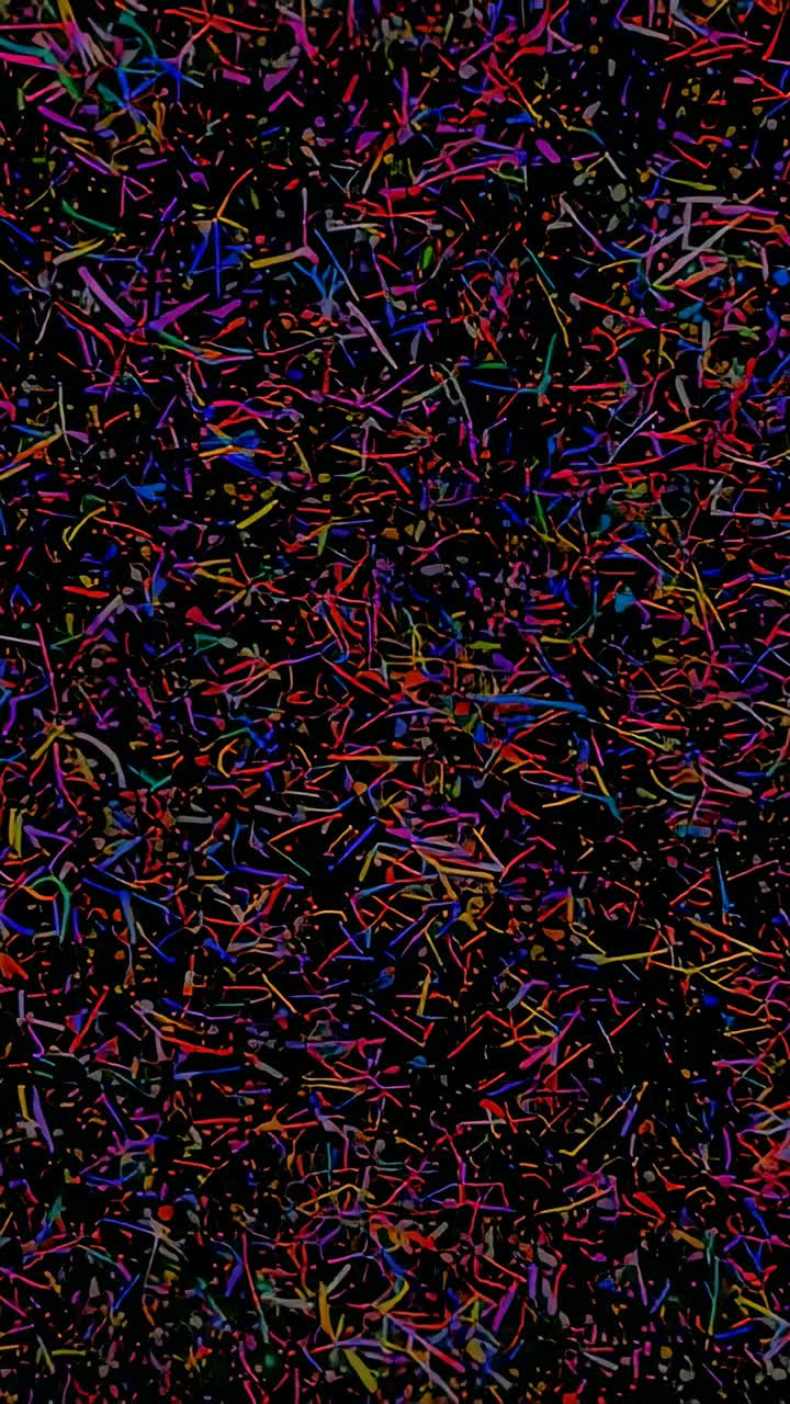 Vertical video: Zooming abstract confetti field, slowly revealing colorful lines and dots on black