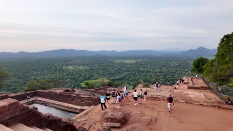 visitors at the top of sigiriya lion rock in sri lanka, enjoying panoramic views and ancient ruins. a popular travel destination showcasing historical architecture and breathtaking landscapes.