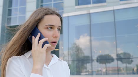 mujer hablando en un teléfono móvil frente a la oficina