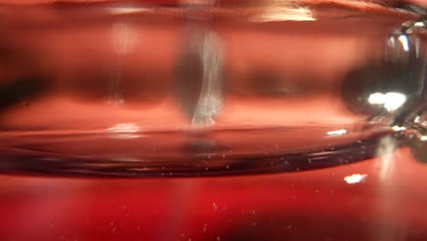 bubbles forming on the surface of a wet beverage in a clear glass, macro shot.