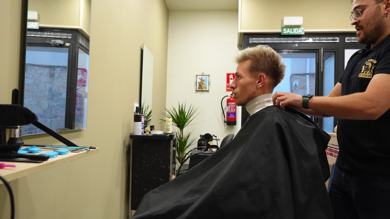 Barber places protective white band around client’s neck before starting haircut
