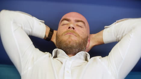 a man leaning back and yawning at home on a sofa couch