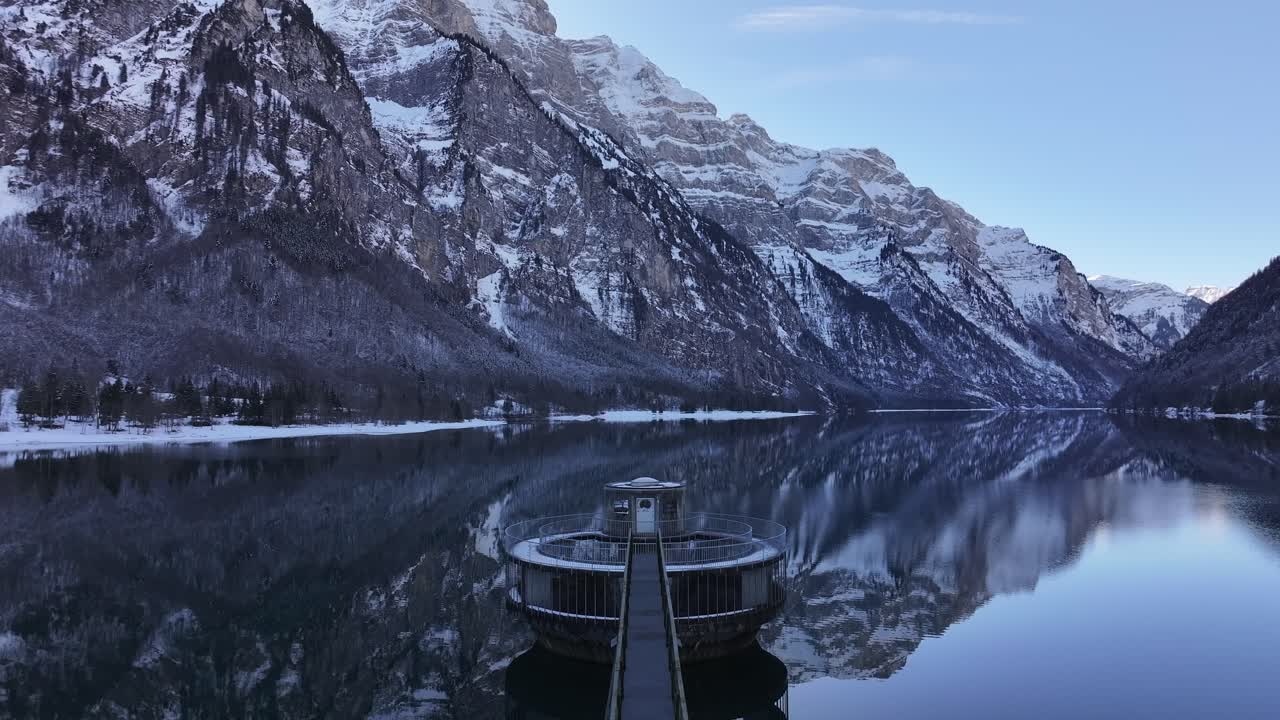 A calm lake surrounded by snowy mountains in Klöntal, Glarus, Switzerland