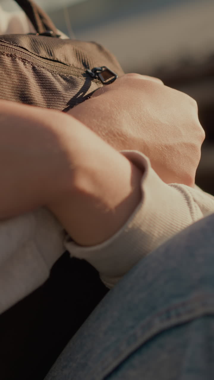 젊은 여성이 따뜻한 빛 아래 가방을 애정으로 들고있는 클로즈업, 부드러운 그림자가 그녀의 부드러운 표정에 깊이를 더하고, 미묘한 흐릿한 배경