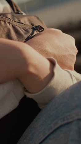 primer plano de una mujer joven sosteniendo afectuosamente su bolsa bajo la cálida luz del sol, con sombras suaves que añaden profundidad a su expresión suave, con un fondo sutil y borroso