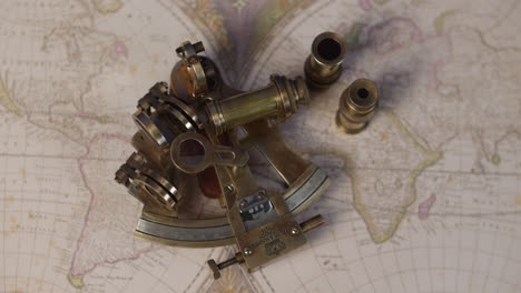 a brass sextent navigation instrument on a vintagemap of the world