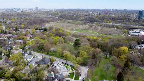 aerial shot flying over a small park with lots of trees in a toronto neighborhood in spring time