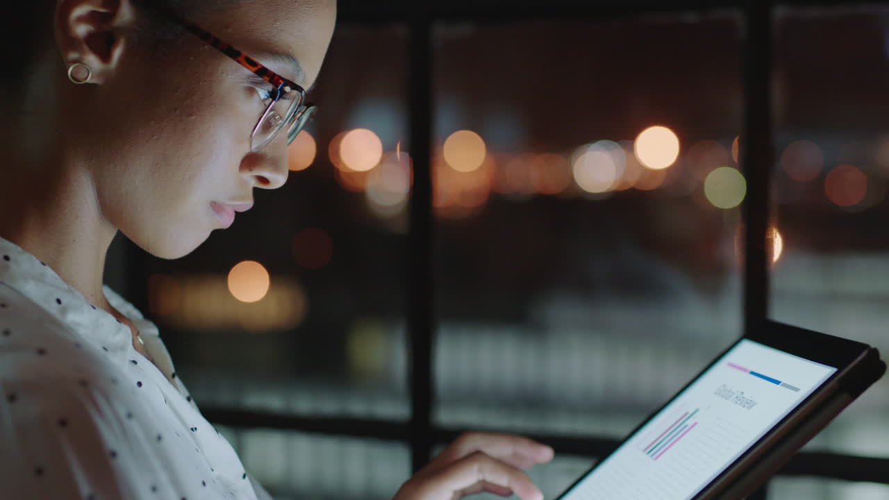cerca hermosa mujer de negocios trabajando hasta tarde usando una tableta navegando datos de investigación estadísticas en la pantalla lluvia de ideas exitoso proyecto fecha límite estrategia mirando por la ventana planificación por delante