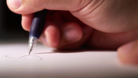 blurry close-up of an individual's hand while scribbling some notes using a pen on a clean white sheet of paper