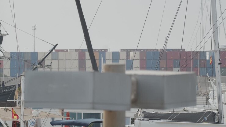 Ferdinand Magellan Nao Victoria carrack boat replica with spanish flag enters wharf in Valencia with containers in the background in slow motion 60fps