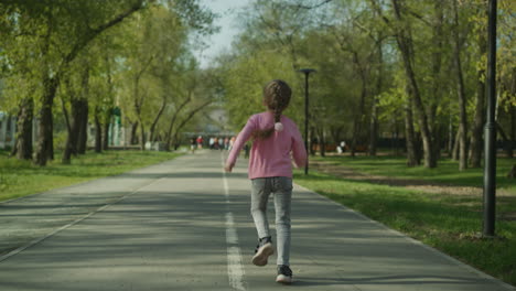 Playful-little-girl-runs-along-empty-road-in-spring-park