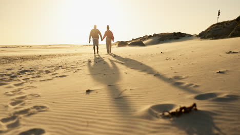 una pareja caminando por una playa al atardecer
