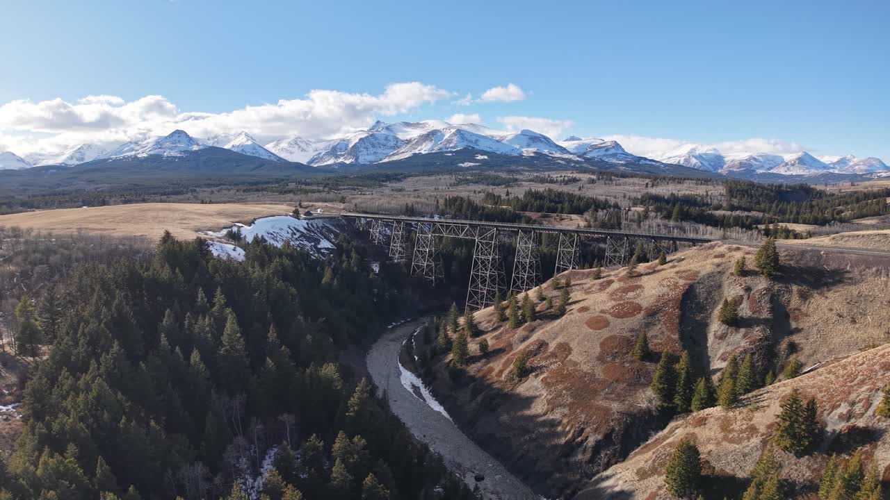 Drönarfilm visar en slingrande flod som skär genom en brun dal med barrskogar och snötäckta berg i fjärran nära Whitefish, Montana, fångad en klar dag.