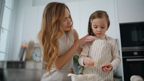 cute child making apple pie with mommy at home. mother straightens daughter hair