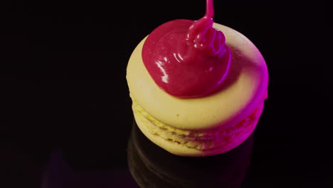 pink drizzled macaron on black background