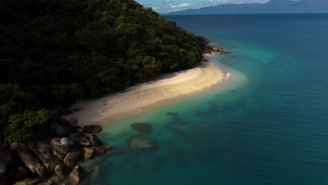 Breite-Rotierende-Drohnenaufnahme-Des-Strandes-Auf-Fitzroy-Island-Mit-Einer-Frau,-Die-Auf-Sand-Läuft