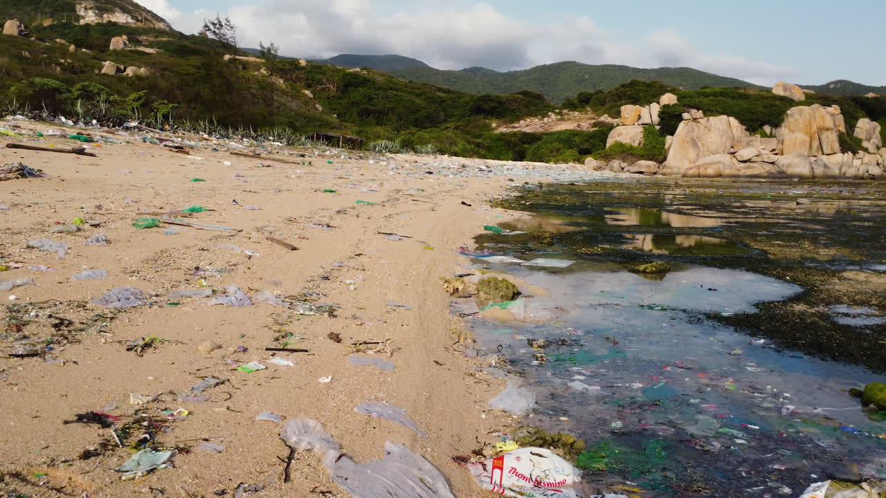 Volo a bassa quota sopra una spiaggia estremamente inquinata con plastica, sporcizia, rifiuti e alghe sulla battigia - Vietnam, Asia