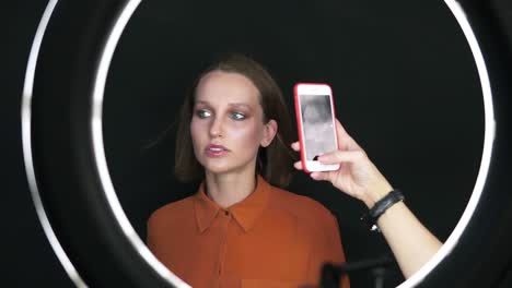 Hermosa-Mujer-Modelo-Posa-Para-La-Cámara-Del-Teléfono-Inteligente-En-El-Estudio.-Mujer-Sensual-Con-Cara-Maquillada,-Pelo-Rubio-Corto-En-Luz-Softbox