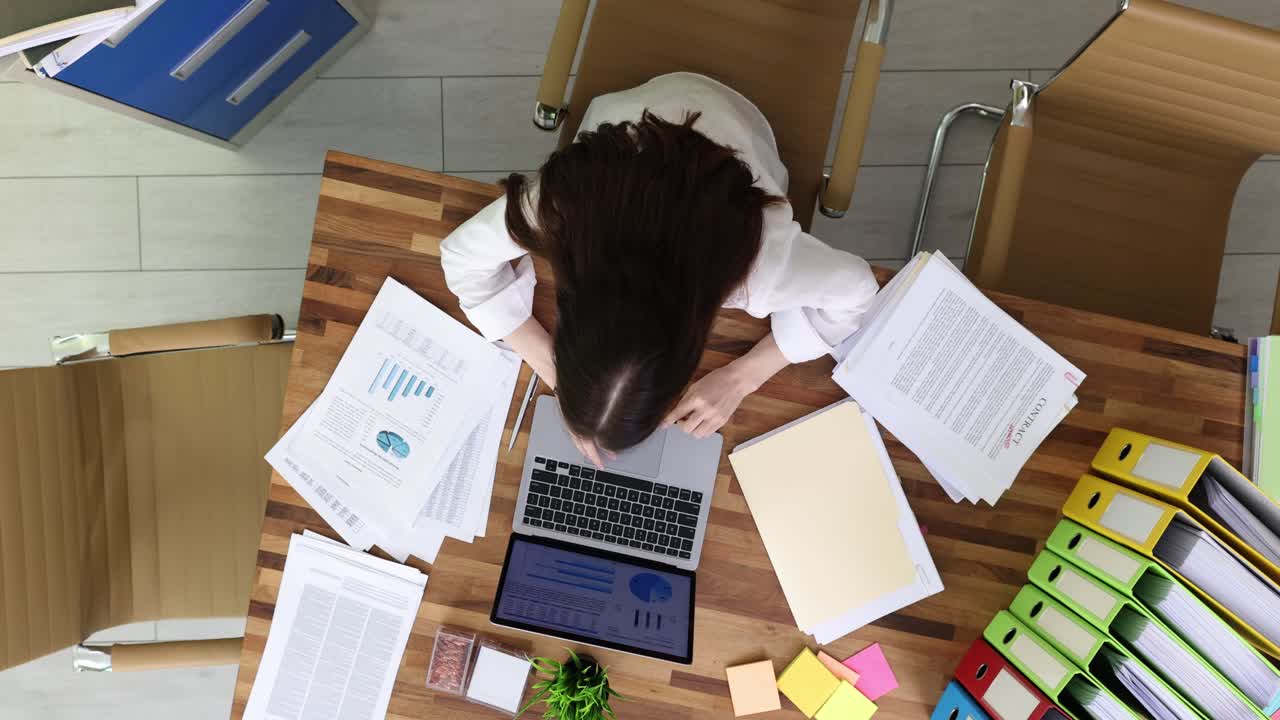 Woman working at her desk with laptop and documents
