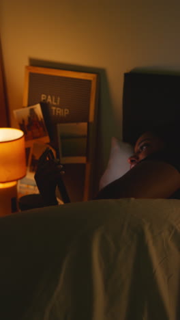 woman reading phone in bed at night