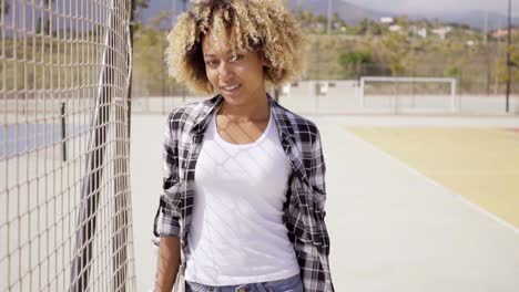 mujer joven con poses de monopatín por cancha de pelota