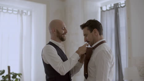 guapo gay caucásico atando su corbata de amante para la ceremonia de boda
