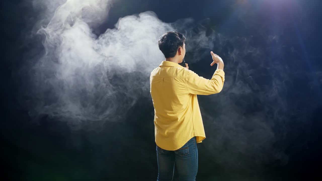 백색 연기 검은 배경에 마이크를 들고 하는 어린 소년의 뒷면
