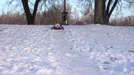 a girl on a snow hill, one goes down on an ice sled