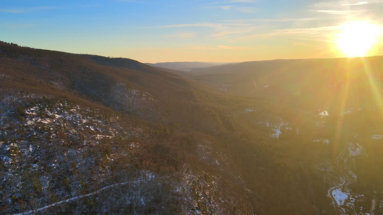 полет над заснеженной горой и глубокой долиной во время зимнего заката