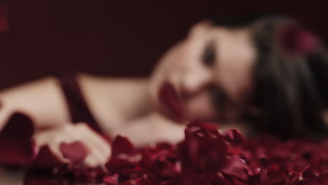 portrait beautiful caucasian woman playing with rose petals blowing sensual female dreaming of intimate fantasy romance indulging desire in red background valentines day concept