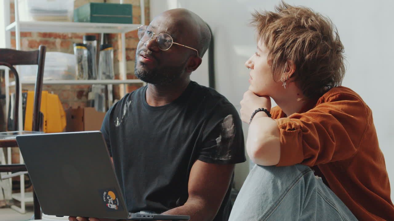 Cheerful Man and Woman Discussing Home Renovation Ideas on Laptop