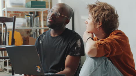 cheerful man and woman discussing home renovation ideas on laptop