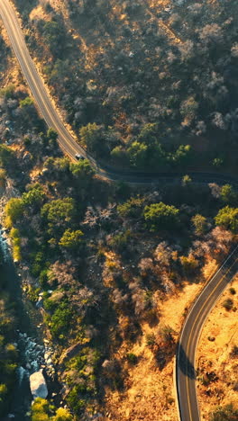 dangerous highway in california mountains. road over the river flowing among the rocks. top view. vertical video