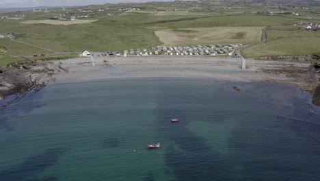 Boats-moored-peacefully-in-narrow-bay,-beach-town-at-Milltown-Malbay