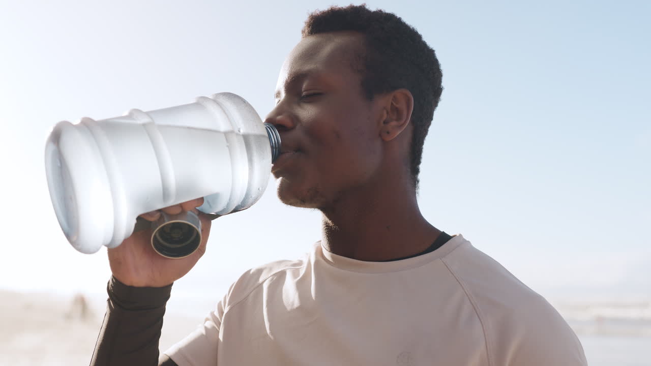 hombre negro, fitness y agua potable en la playa