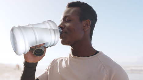 black man, fitness and drinking water on beach