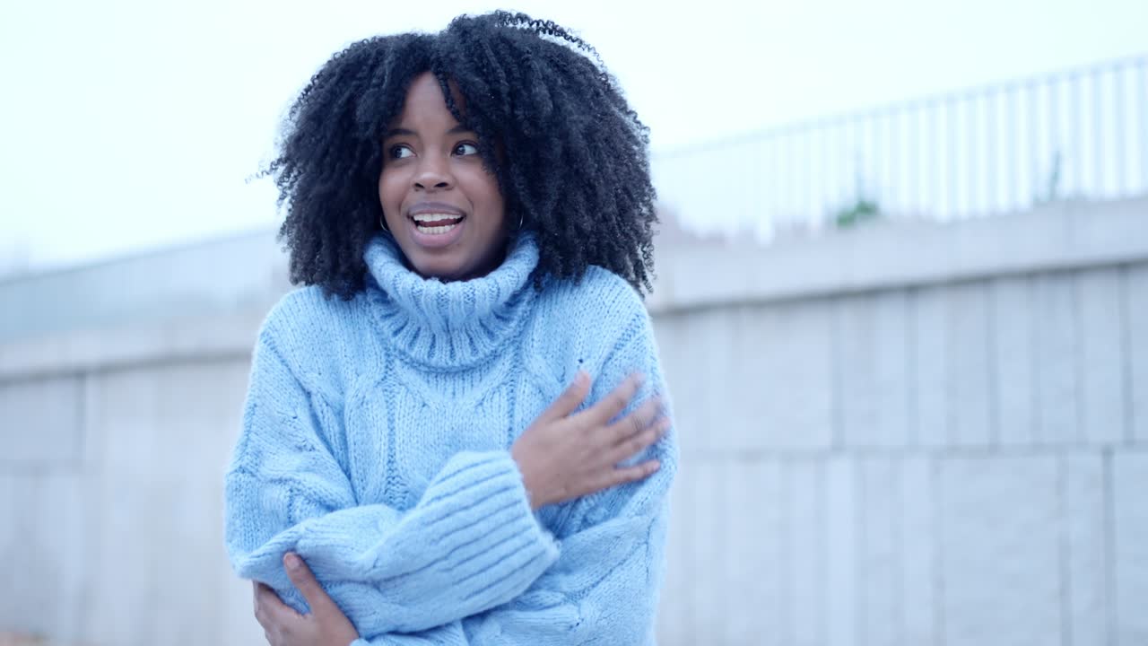 African woman gesturing cold in the street