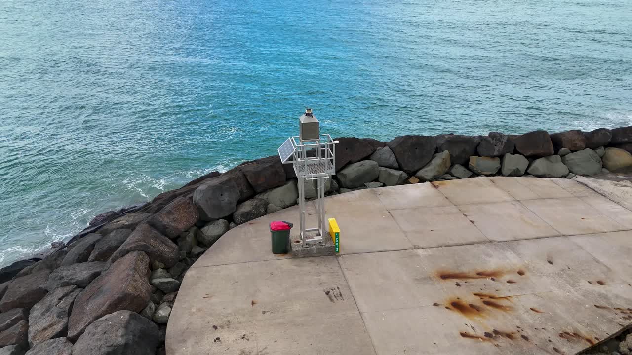 Aerial footage of a rocky jetty extending into the ocean, captured on a clear day along the Great Ocean Road